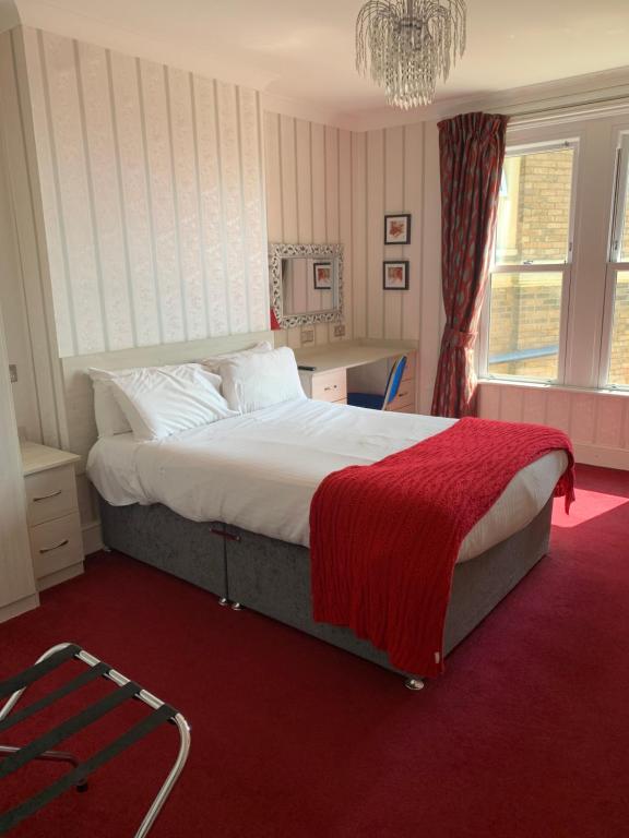 ボーンマスにあるHotel Balmoralのベッドルーム1室(赤毛布付きの大型ベッド1台付)