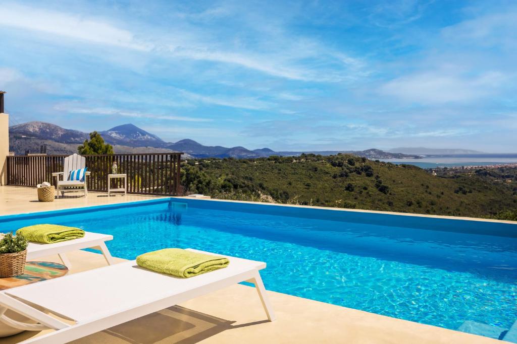 a swimming pool with a view of the ocean at Akrolithos Villas in Kouvaláta