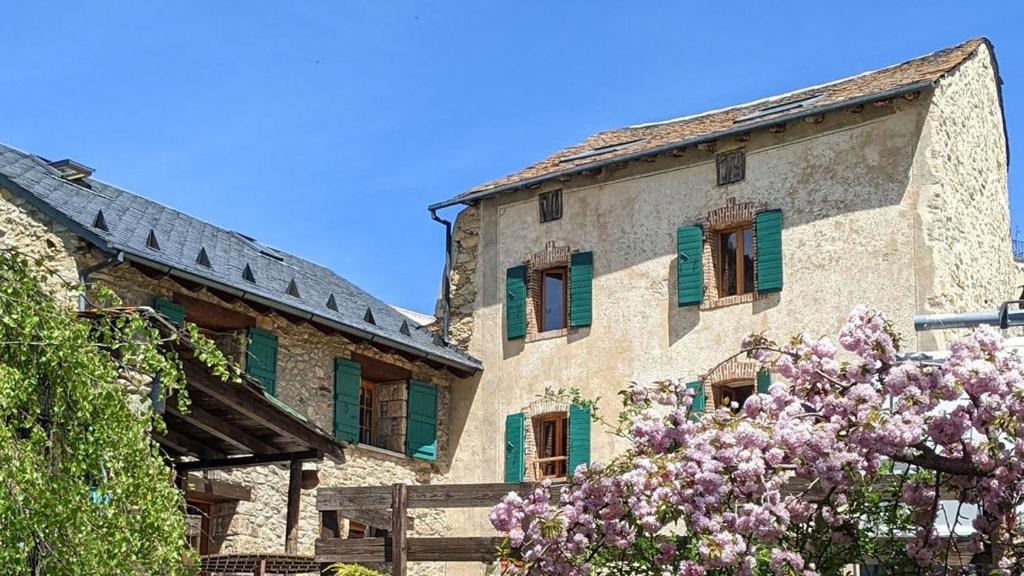 un bâtiment avec des fenêtres vertes à volets et un arbre à fleurs dans l'établissement Cottage des Pléiades - Station de ski accessible à pieds, aux Angles