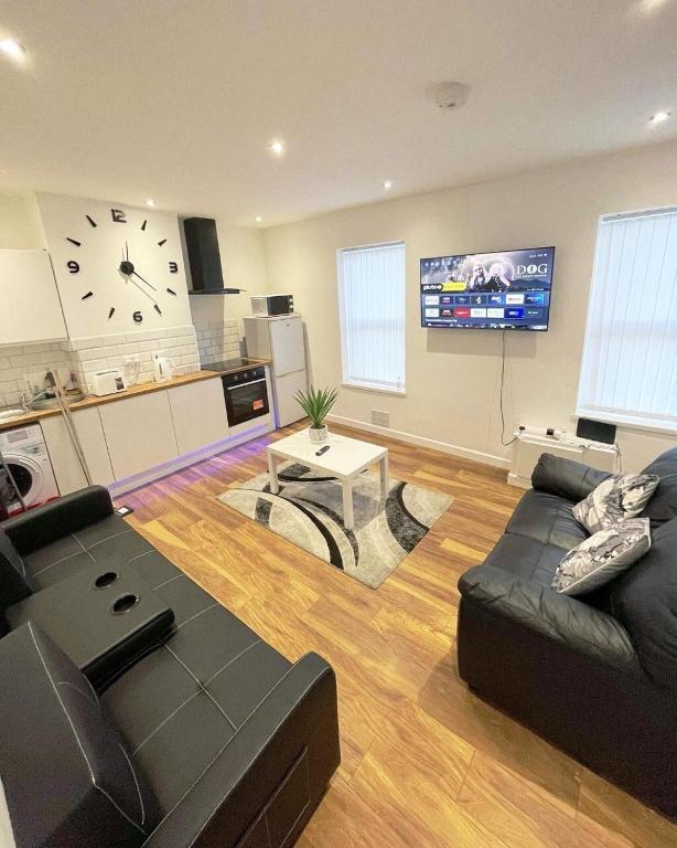 a living room with a couch and a clock on the wall at AK Serviced Apartments - Exclusive Two-Bedroom Apartment in Cardiff