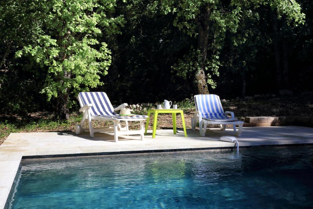 - deux chaises et une table à côté de la piscine dans l'établissement La Cerisaie, maison spacieuse en Lubéron, à Saint-Martin-de-Castillon