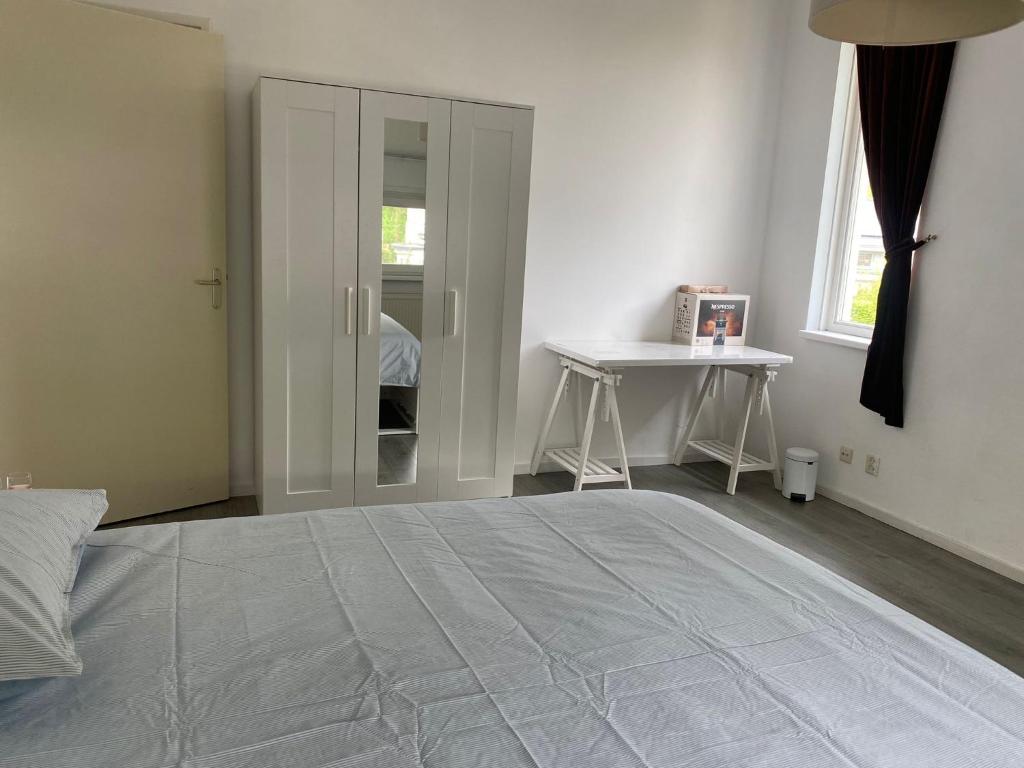 a white bedroom with a bed and a desk at De Keizersmantel in Son