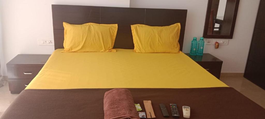 Cama con sábanas amarillas y almohadas amarillas en P N A Apartments - Manpada, en Thane