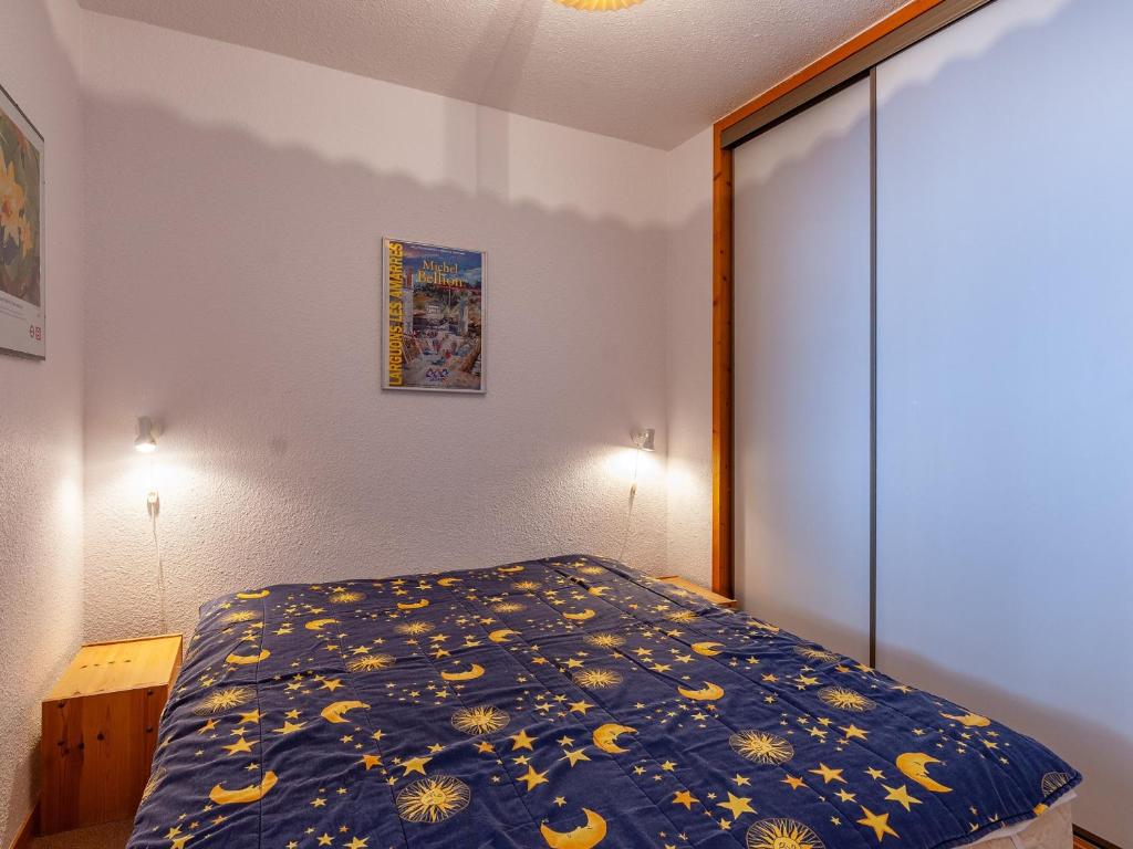 a bedroom with a bed with a blue comforter at Appartement Méribel, 3 pièces, 6 personnes - FR-1-355-48 in Méribel