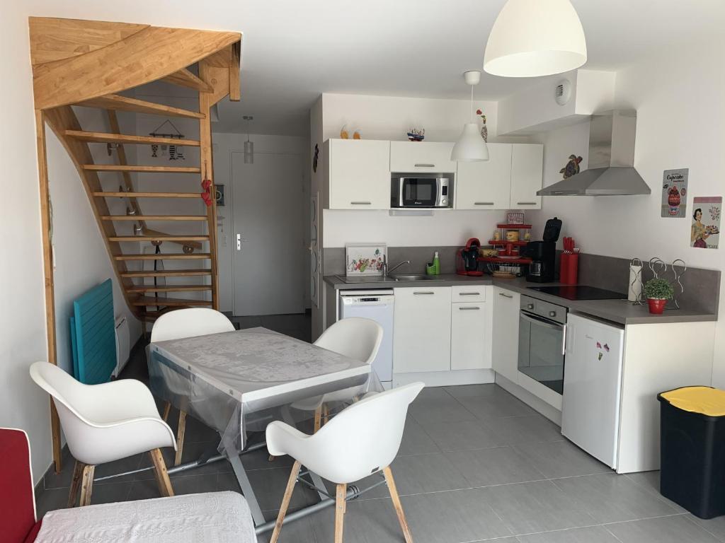 een keuken met witte kasten en een tafel en stoelen bij Maison Quend, 3 pièces, 4 personnes - FR-1-482-45 in Quend