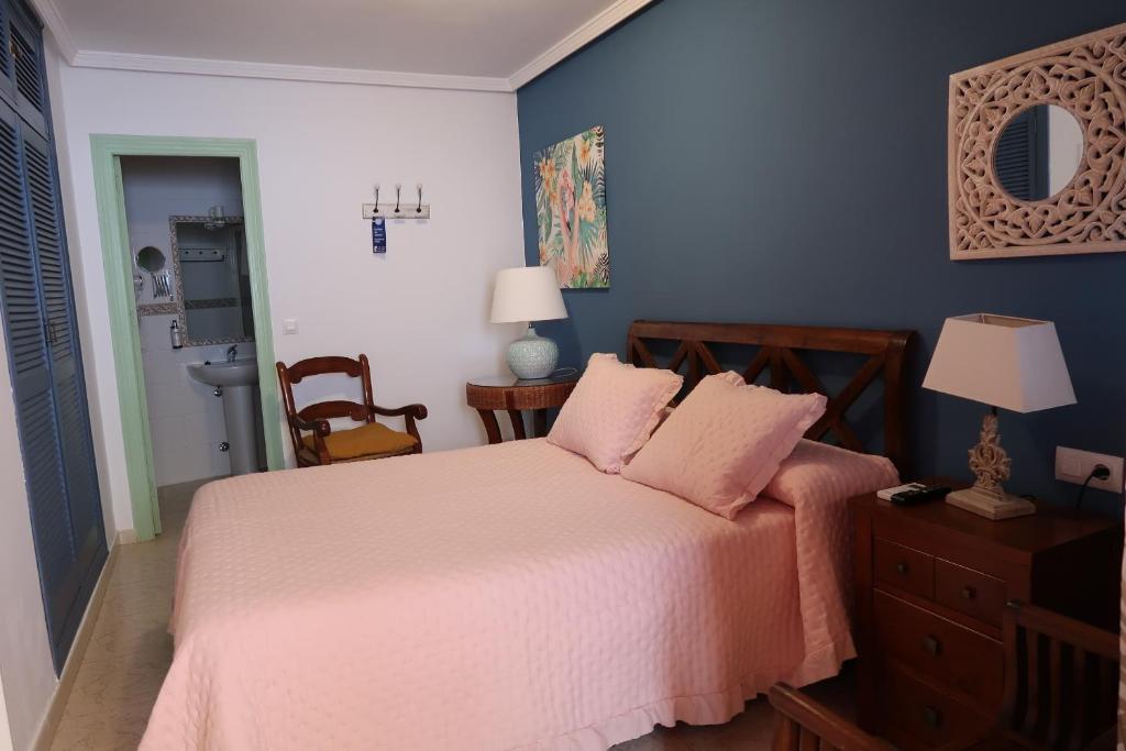 a bedroom with a bed with pink sheets and blue walls at Rompeolas Playa in Chipiona