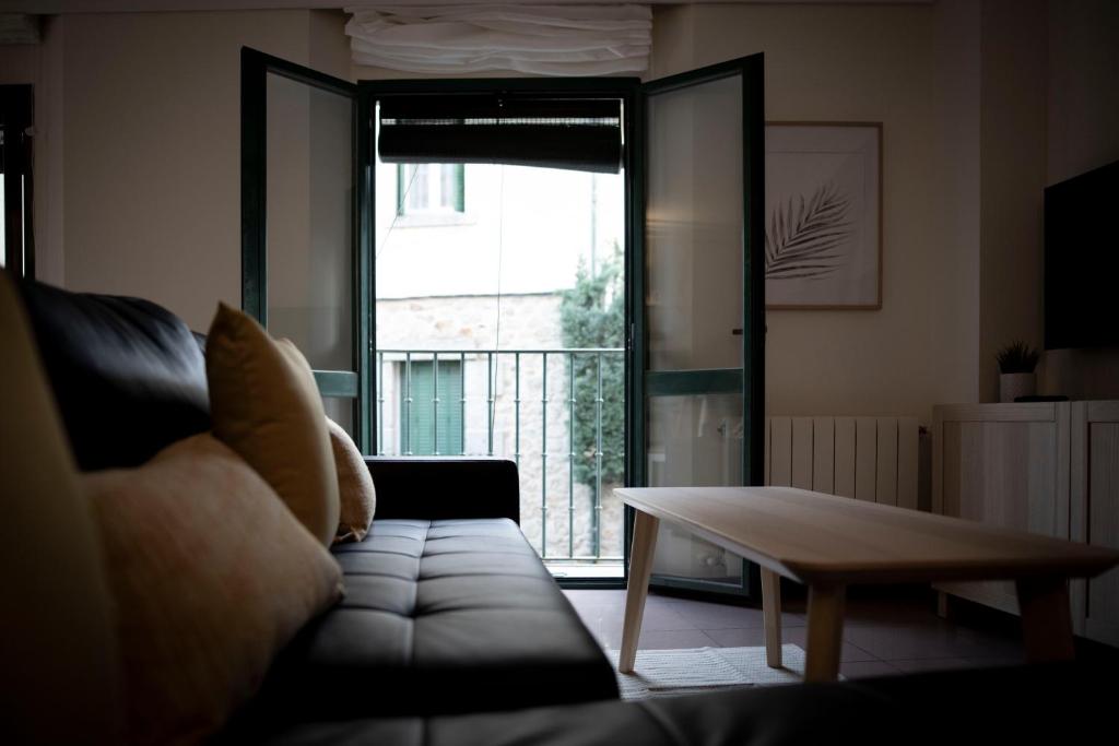 sala de estar con sofá, mesa y ventana en Apartamento Exterior 2 dormitorios en CENTRO HISTÓRICO, en San Lorenzo de El Escorial