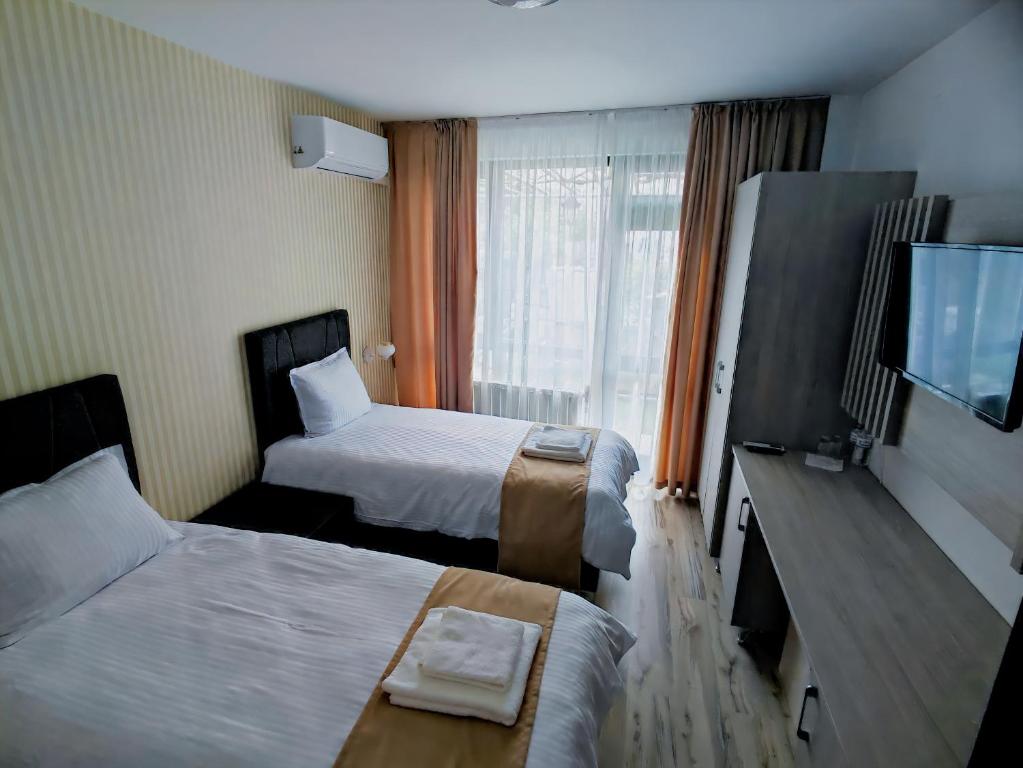 a hotel room with two beds and a flat screen tv at HOTEL GOLDEN CITY in Zlatograd