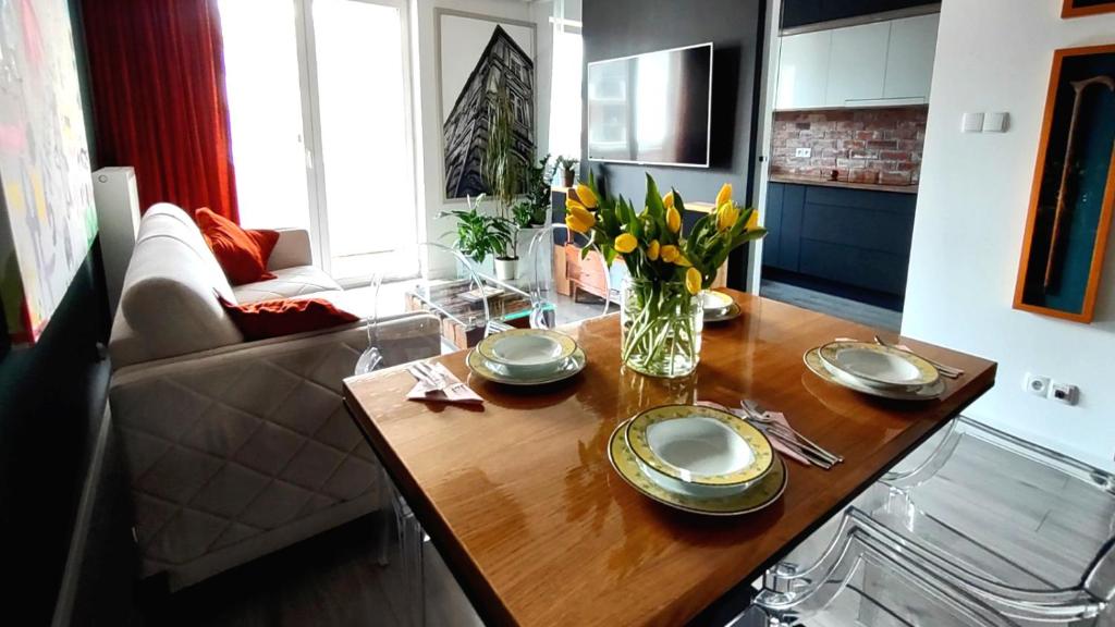 una sala de estar con una mesa con platos y flores. en Apartament w lesie nad rzeką, en Dywity