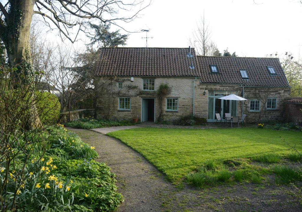 a large stone house with a grass yard at Coach House Cottage in Middleton