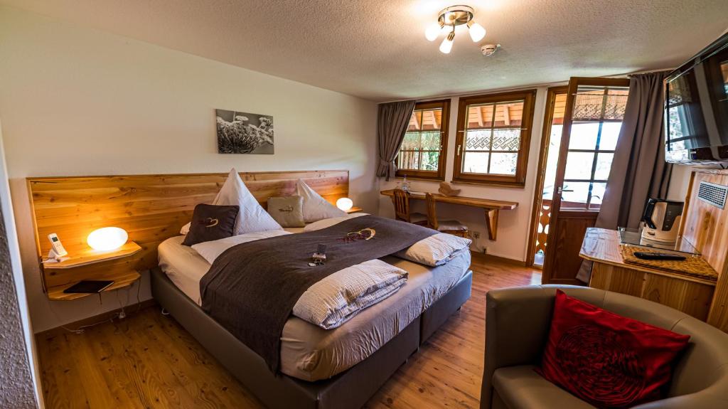 a bedroom with a large bed and a chair at Gästehaus Holzer Kreuz - Gästezimmer Veilchen für 2 Personen inkl Landfrühstück in Fröhnd