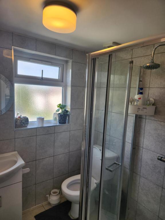 a bathroom with a shower and a toilet and a window at Private Room in Ilford