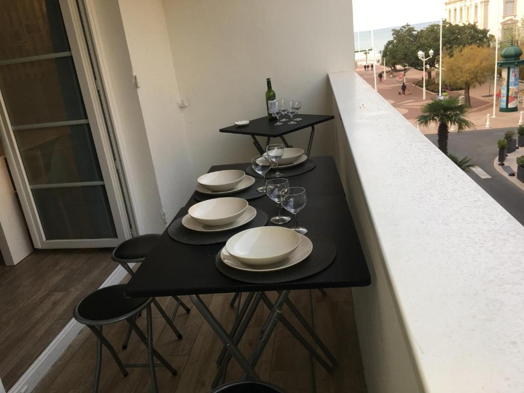 une table avec des assiettes et des verres à vin sur un balcon dans l'établissement Centre-ville Arcachon, T3 rénové avec aperçu mer, proche plage et gare - FR-1-374-77, à Arcachon