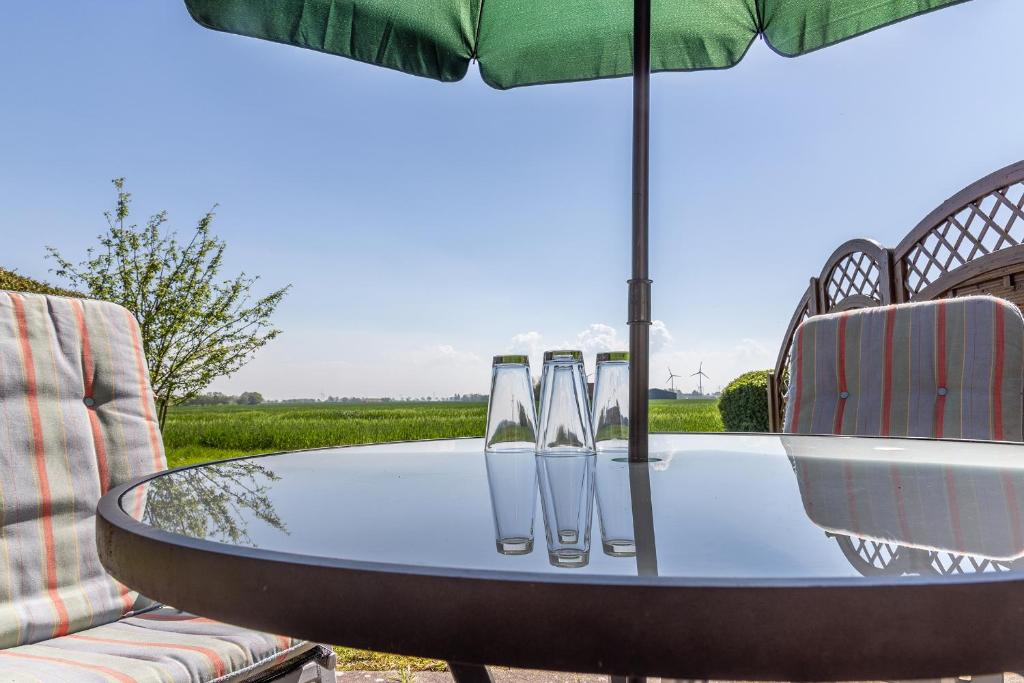 uma mesa com copos de vinho e um guarda-chuva em 50152... em Carolinensiel