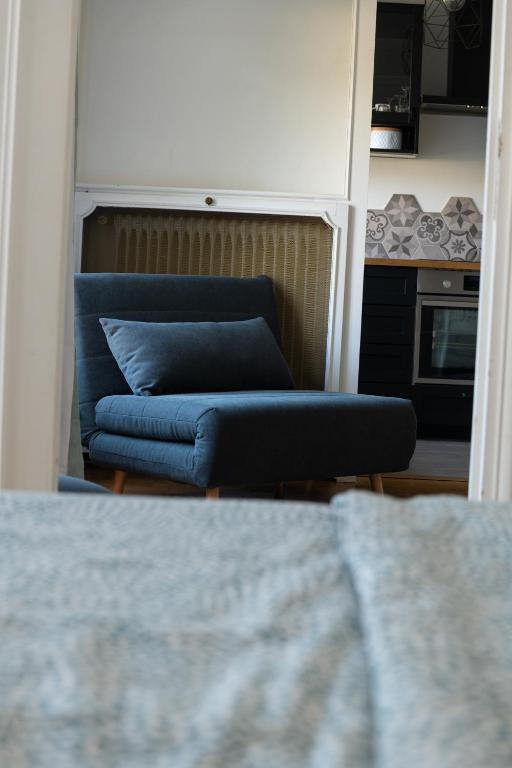 a blue couch in a room with a kitchen at Best place à 15 min de Paris in Saint-Maur-des-Fossés