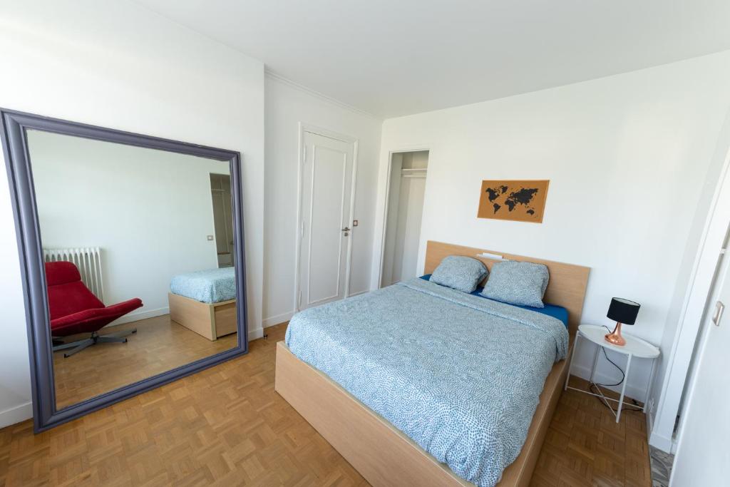 a bedroom with a mirror and a bed and a chair at Best place à 15 min de Paris in Saint-Maur-des-Fossés