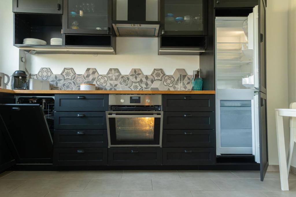 a kitchen with black cabinets and an oven at Best place à 15 min de Paris in Saint-Maur-des-Fossés