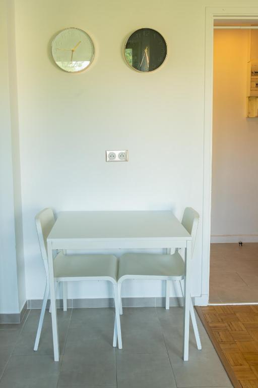 a white table with two chairs and a clock on a wall at Best place à 15 min de Paris in Saint-Maur-des-Fossés