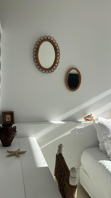 Sala de estar blanca con sofá blanco y espejo en Hotel La Potiniere, en Hyères