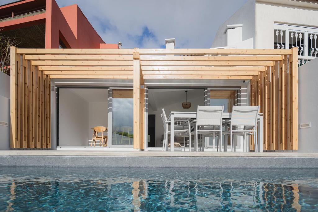 a villa with a pool in front of a house at Figueiras House Pópulo Beach in Ponta Delgada