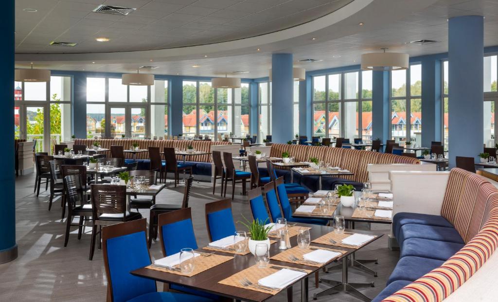 ein Restaurant mit Tischen, Stühlen und Fenstern in der Unterkunft Precise Resort Hafendorf Rheinsberg in Rheinsberg
