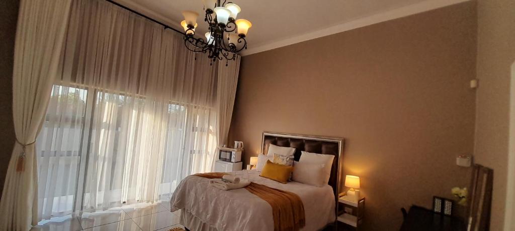 a bedroom with a bed with a window and a chandelier at The Dream Guesthouse in Ermelo