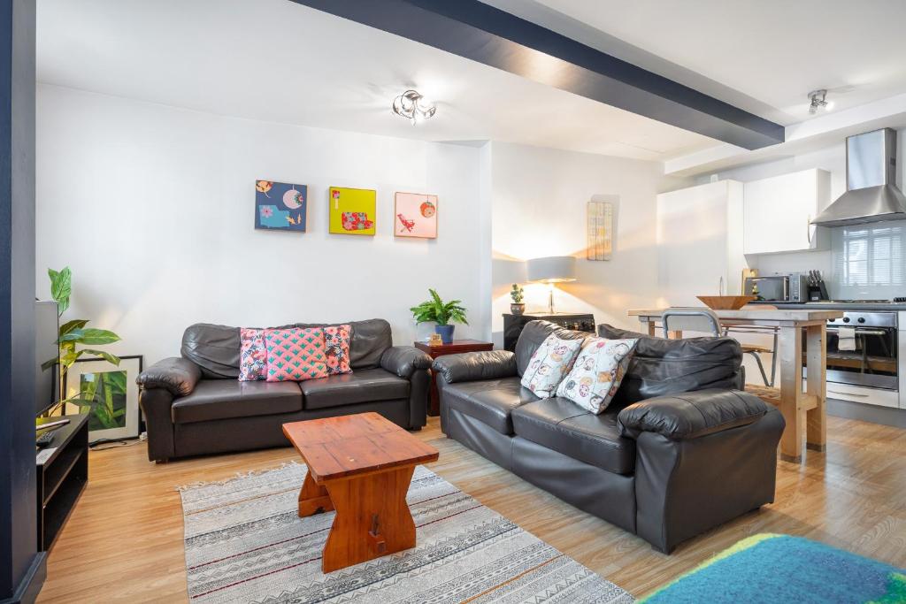 a living room with two leather couches and a table at Spitalfields one bedroom apartment in London