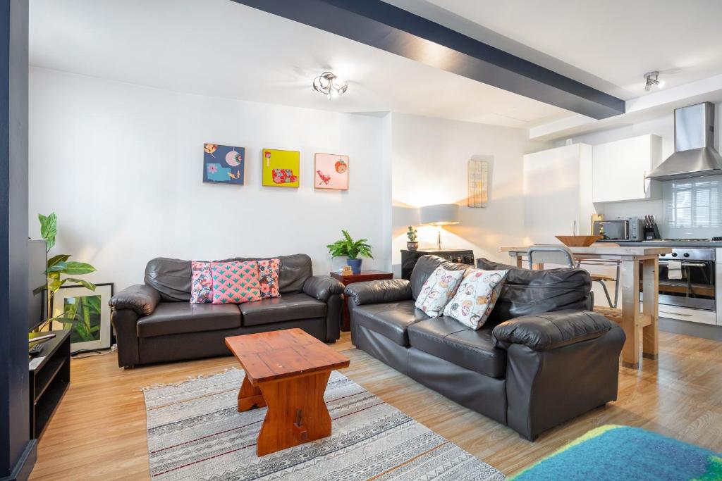 una sala de estar con 2 sofás de cuero y una mesa. en Spitalfields one bedroom apartment, en Londres