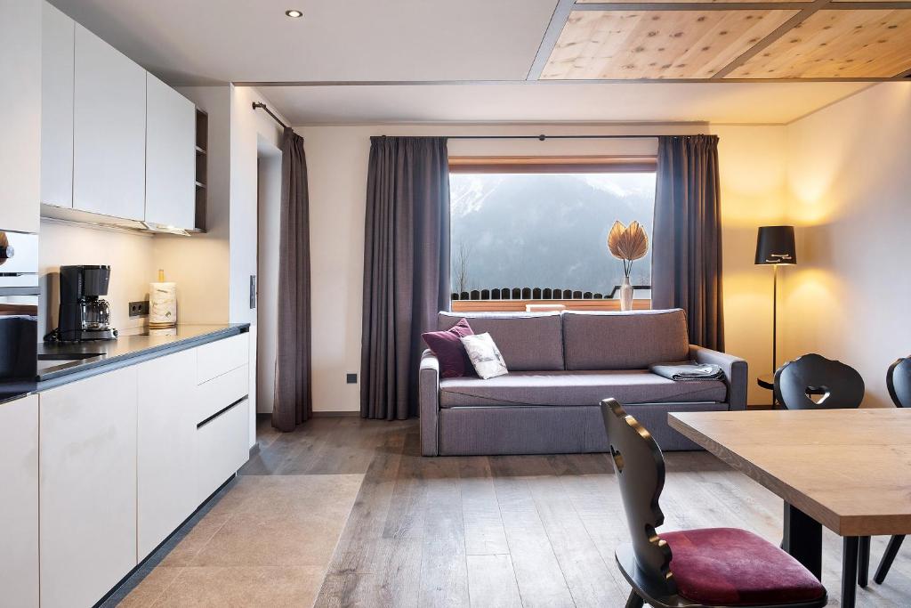 a kitchen and living room with a couch and a table at Angerle Alm Apt König Laurin in Carezza al Lago