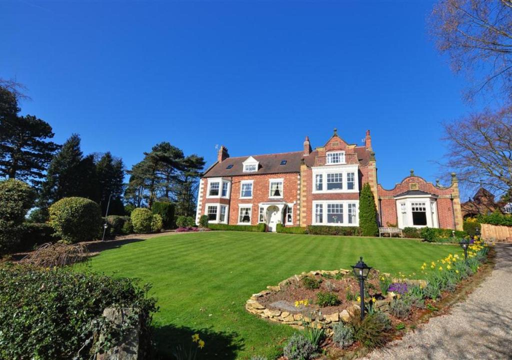 a large brick house with a large yard at Church Beck House in Scalby