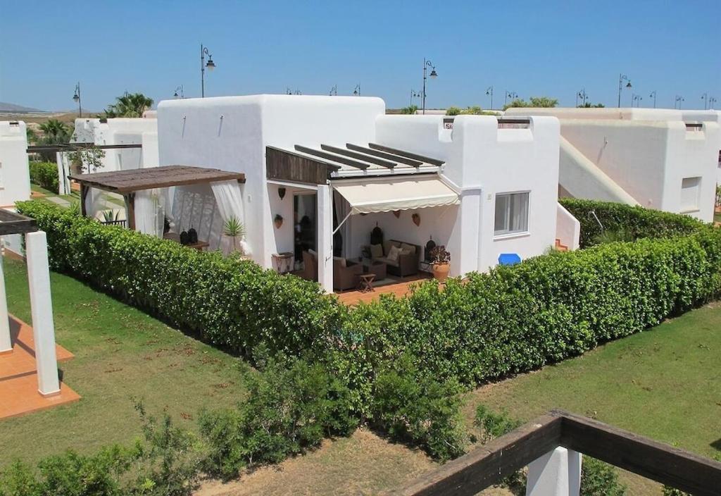 uma casa branca com uma sebe à frente. em Casa la Vida - Golf villa with private pool em Alhama de Múrcia