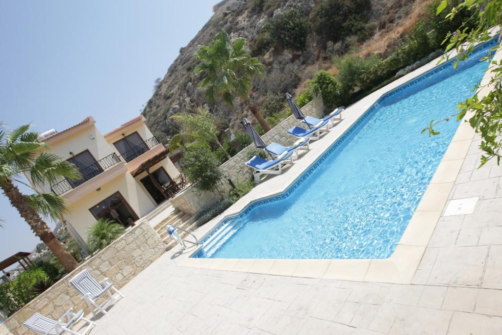 a swimming pool with chairs and a mountain at A three-bedroom villa with a private pool and landscaped garden Wi-Fi in Pissouri