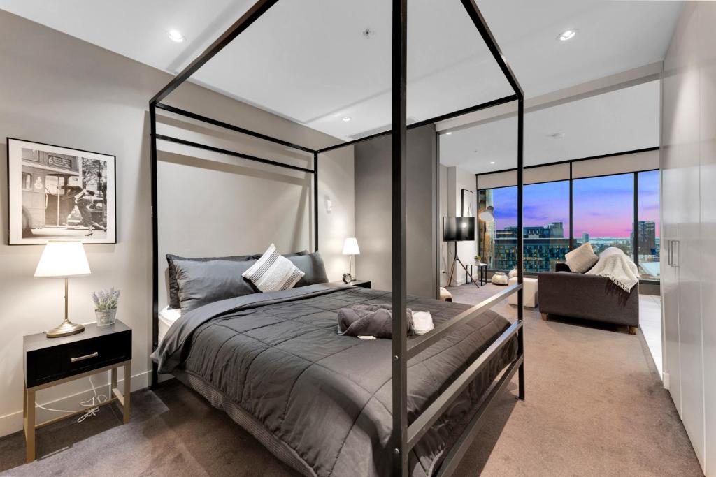 Opulent Level 25 Condo with Breathtaking Views في ملبورن: غرفة نوم بسرير كبير وأريكة