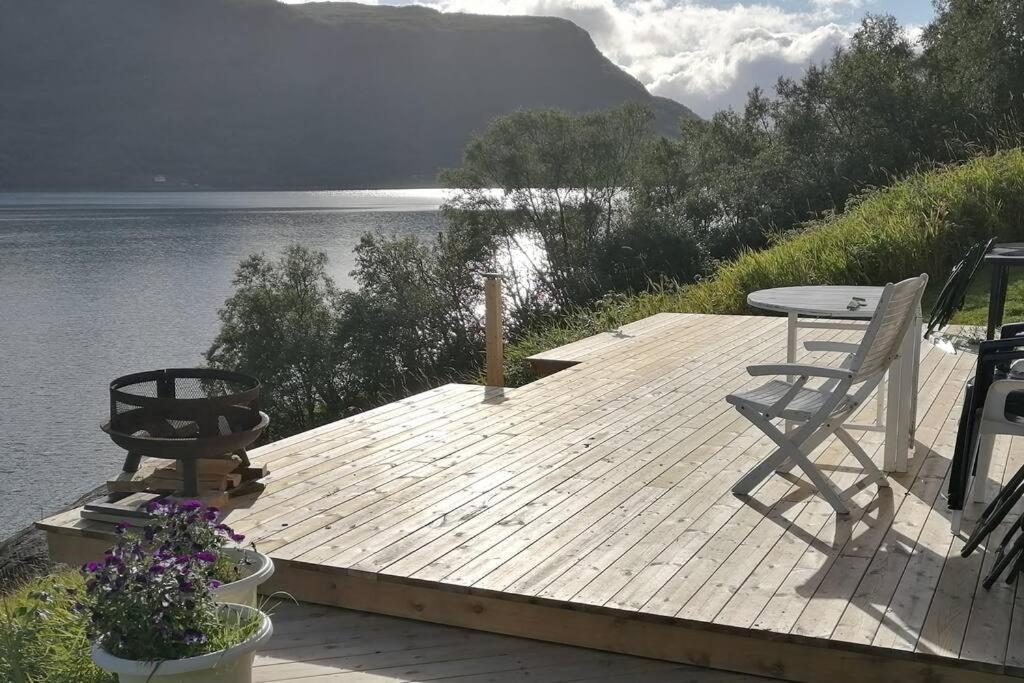 a wooden dock with a table and chairs on the water at Beautiful Lavangsnes, sea , private beach, boat. 