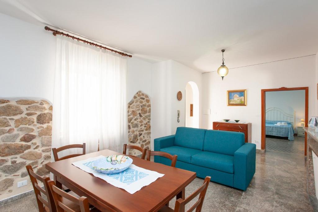 a living room with a table and a blue couch at Casa Irgoli - Sardegna in Irgoli