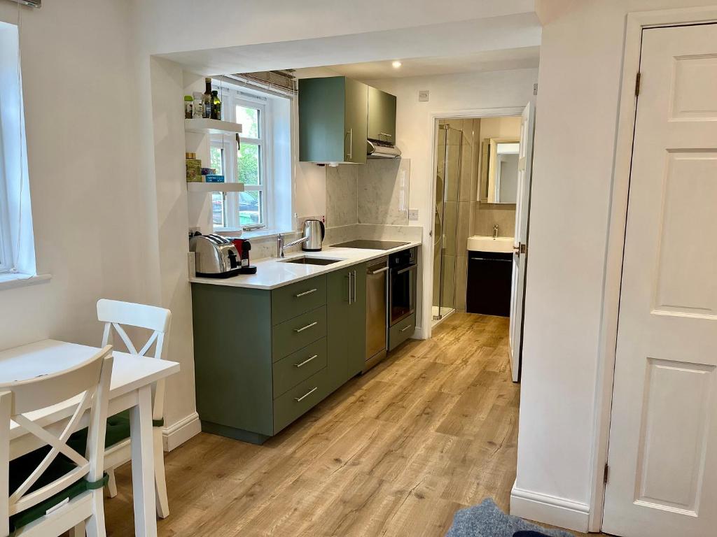a kitchen with green cabinets and a wooden floor at Studio at The Old Vicarage in Abingdon
