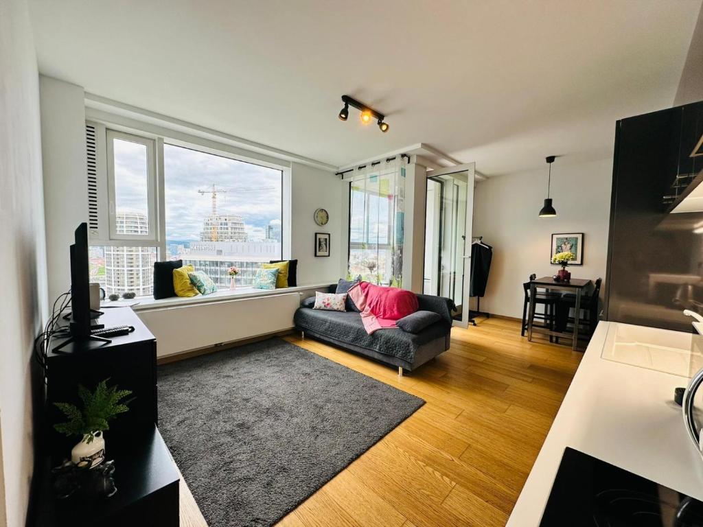 a living room with a couch and a large window at Apartments in Panorama City on 25th floor - amazing view close to Old town in Bratislava