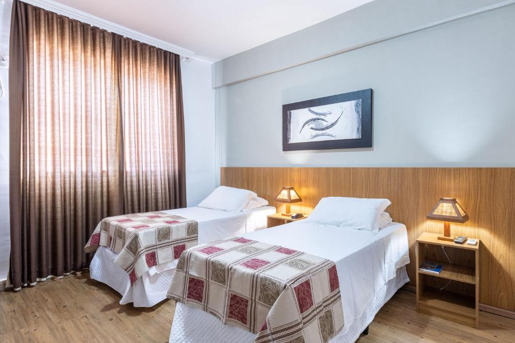 a hotel room with two beds and a window at Ville de Montagne Hotel in Brumadinho