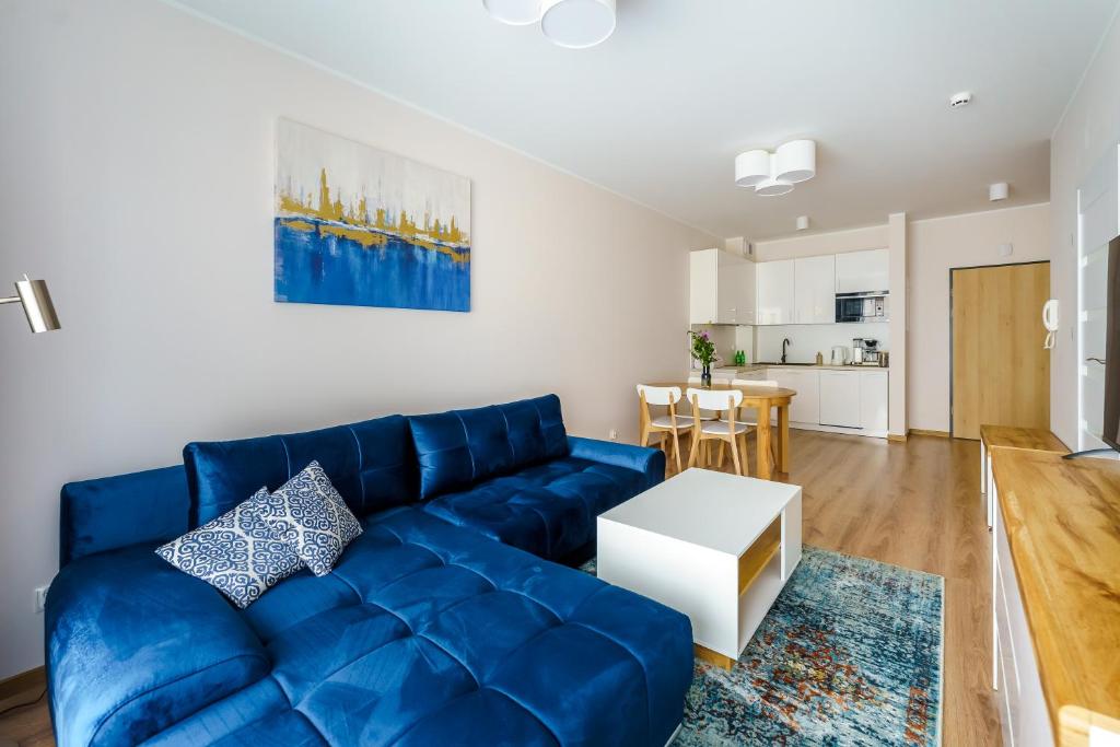 uma sala de estar com um sofá azul e uma mesa em Apartamenty SUNSET RESORT SurfingBird Grzybowo em Grzybowo