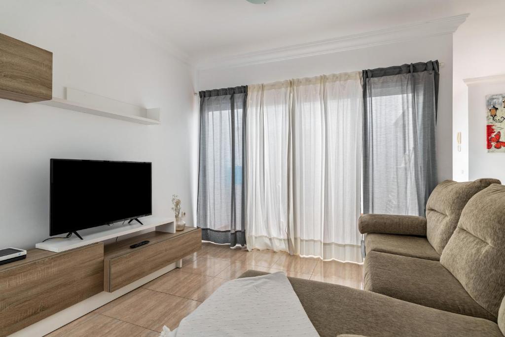 Una sala de estar con un televisor de pantalla plana y un sofá. en Ganivet Home, en Arrecife