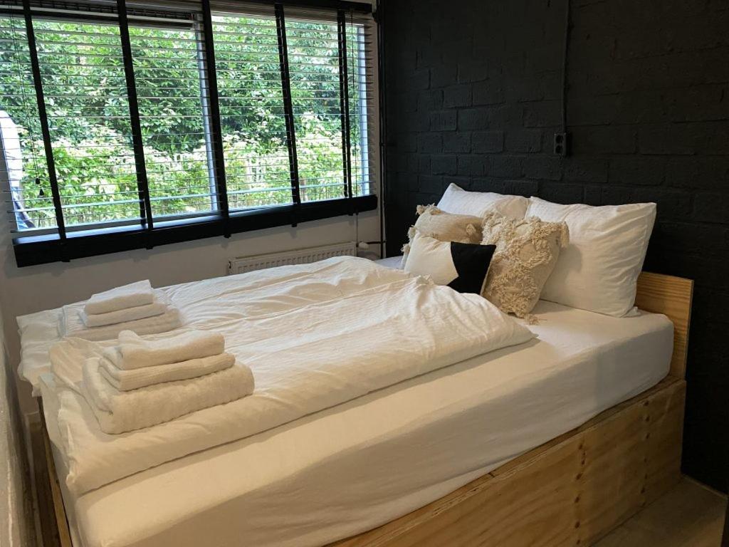 Una cama con sábanas blancas y toallas. en Wellness Cabin Nulytø 24, en Rheezerveen