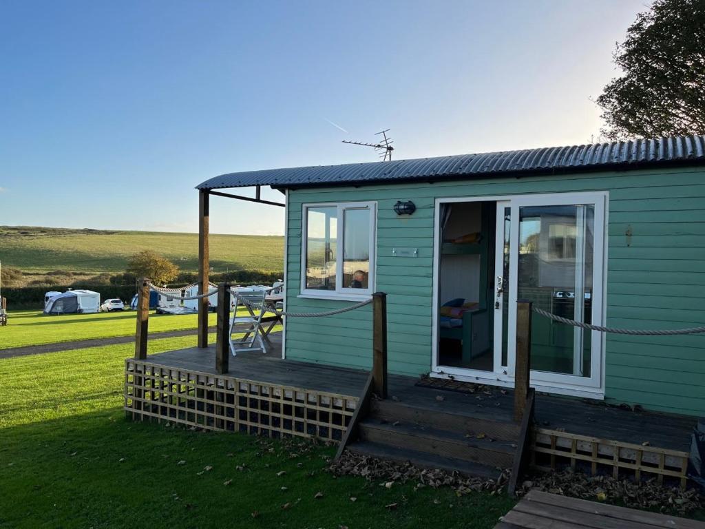 a green tiny house with a porch and a deck at Dune Shepherds Hut in Penally