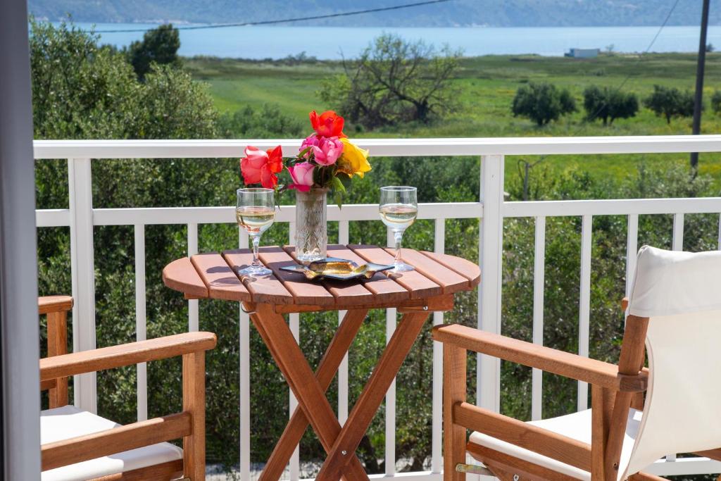 een tafel met wijnglazen en bloemen op een balkon bij SEA & OLIVES HOUSE in Lixouri