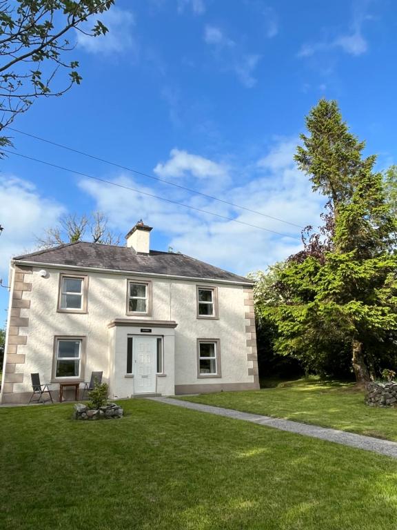 una gran casa blanca con un patio de césped en The Rathmore House, en Roscommon
