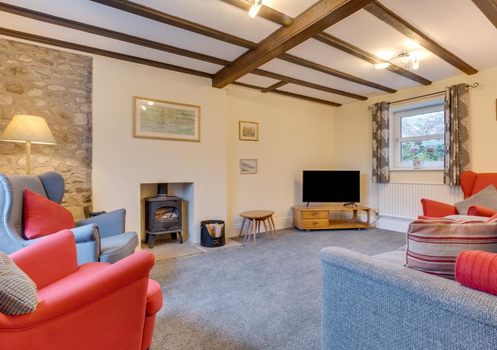uma sala de estar com sofás, uma televisão e uma lareira em Blacksmiths Cottage em Catterick Bridge