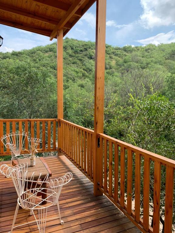 a wooden deck with a table and chairs on it at Cabañas Namaskar in Villa Serranita