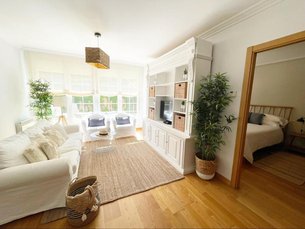 uma sala de estar com um sofá branco e uma televisão em BAKEA Apto con jardín privado em Bakio