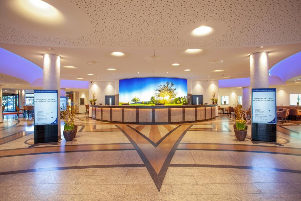 eine Lobby mit einem großen Bildschirm in einem Gebäude in der Unterkunft Sauerland Stern Hotel in Willingen