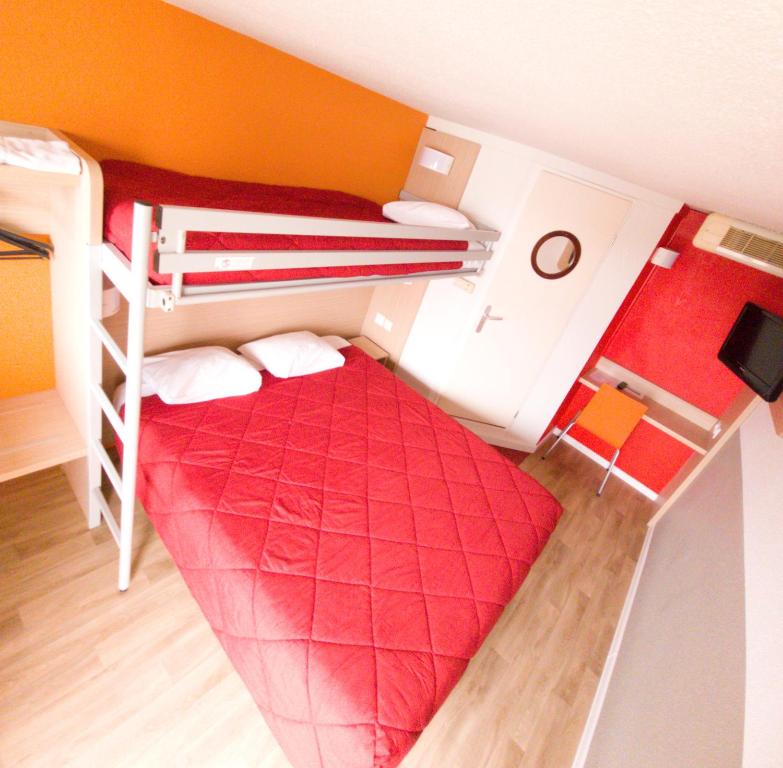 a small room with a bunk bed and a red comforter at Premiere Classe Metz Nord - Semecourt in Fèves