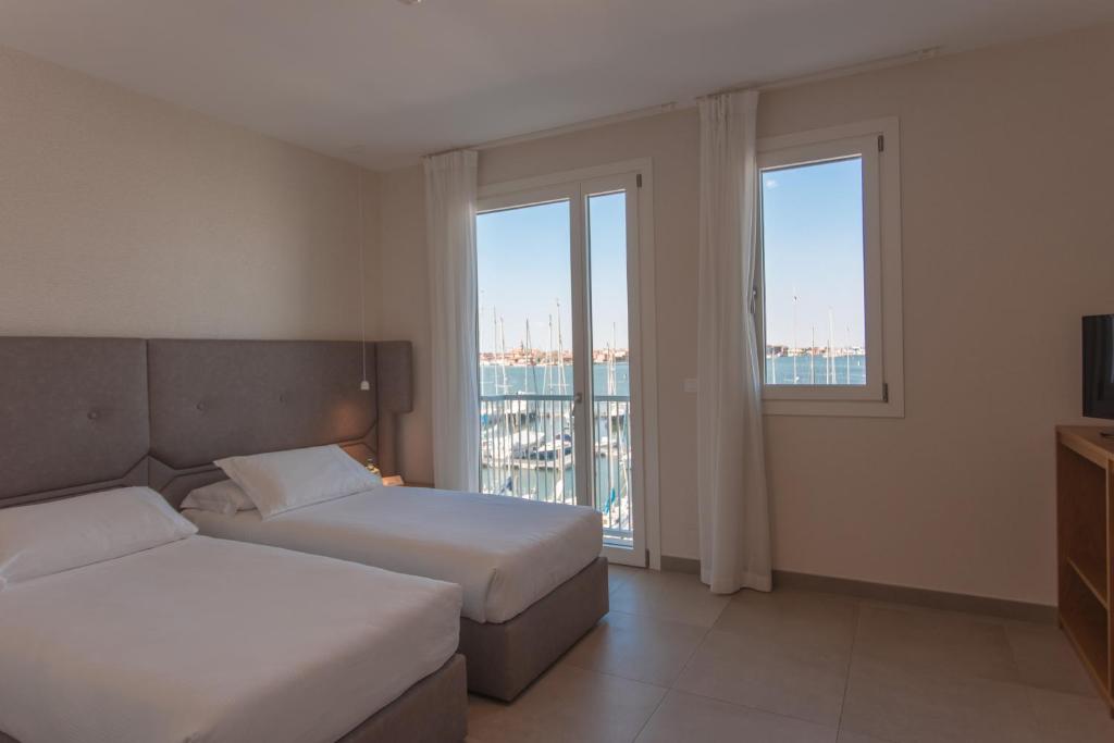 a hotel room with two beds and two windows at Mosella Suite Hotel in Sottomarina